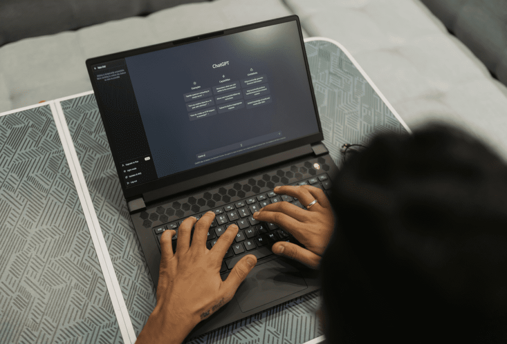 Person using a laptop with an AI chat interface, illustrating how AI tools enable scalable scam automation and modern AI fraud techniques.